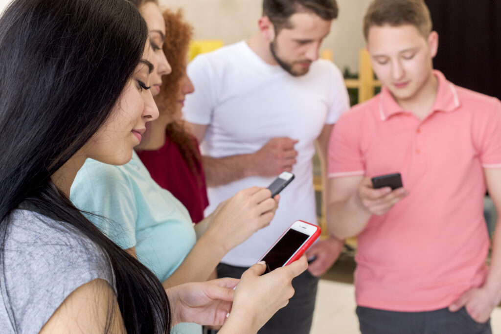 Grupo de jovens usando celulares, exemplificando o evangelismo digital no WhatsApp.